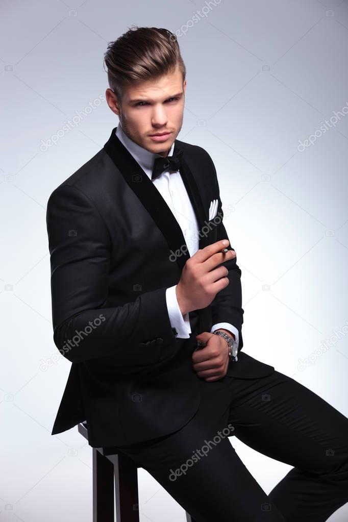 business man sits on chair with cigarette in hand