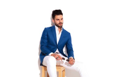 güneş gözlüğü tutan düşünceli zarif adam sandalyede oturur