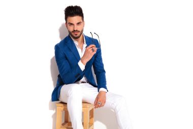 zarif genç adam oturuyor ve tutan güneş gözlüğü 