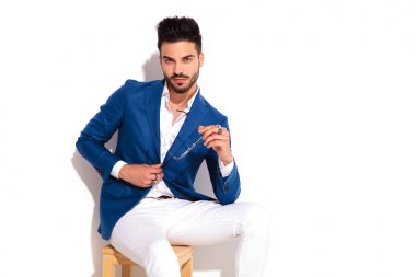 oturmuş zarif adam güneş gözlüğü ve buttining onun takım tutar