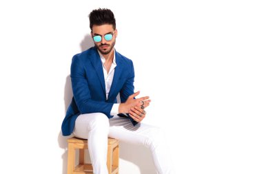 zarif adam sandalye ve sürtünme pal üzerinde oturan güneş gözlüğü takıyor