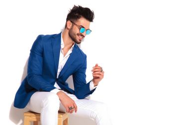 sandalyede oturan zarif genç adam gülen yan görünüm