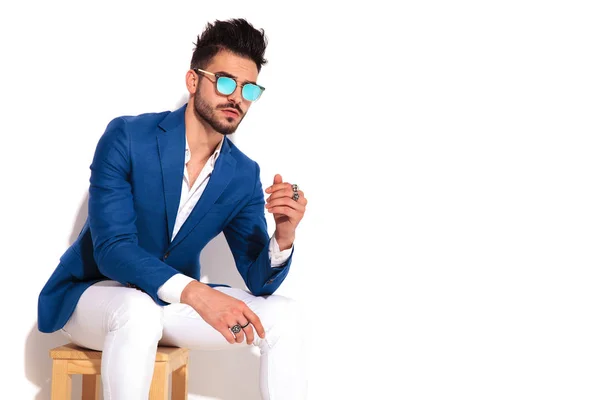 Seated man in blue suit and sunglasses looks to side — Stock Photo, Image