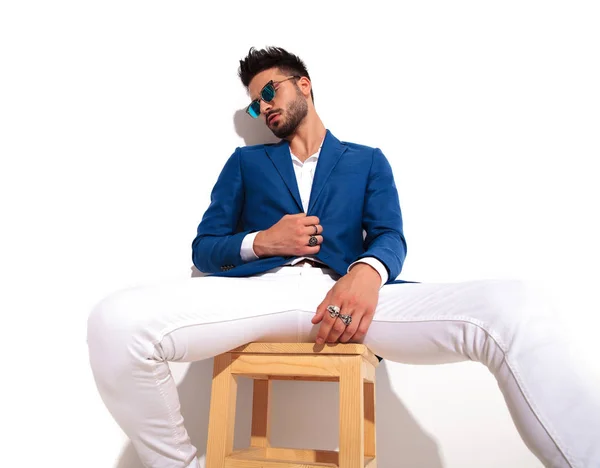 Eleganta mannen bär solglasögon sitter på stol — Stockfoto