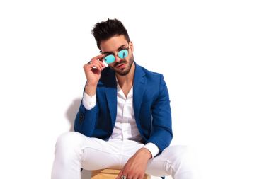 moda erkek model oturma ve güneş gözlüklerini holding