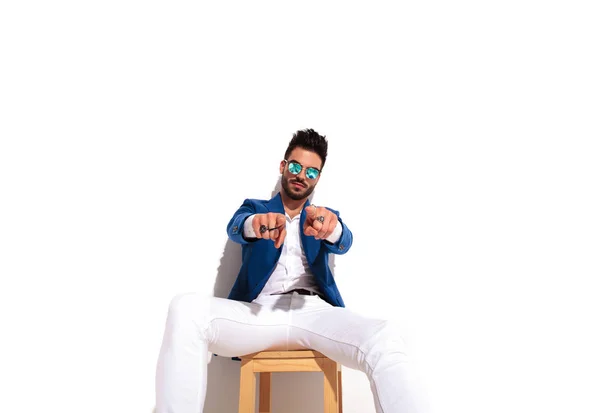 Poważne moda mężczyzna siedzi i wskazującym obiema rękami — Zdjęcie stockowe