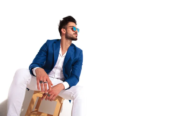 Sitzender Mode junger Mann blickt zu etwas auf — Stockfoto