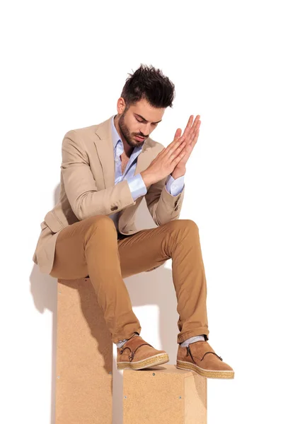 Triste giovane uomo strofinando le palme e si siede — Foto Stock