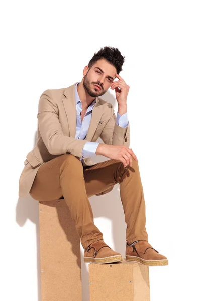 Thoughtful young business man sitting on wooden boxes — Stock Photo, Image