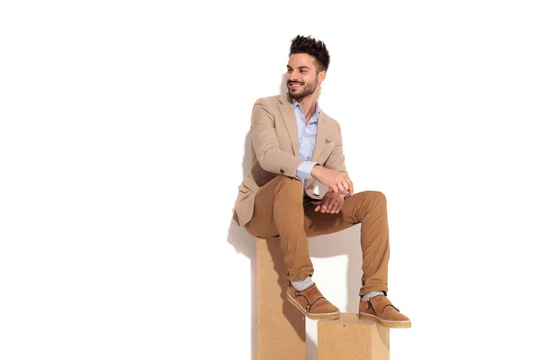 Смеющийся молодой бизнесмен сидит на деревянных коробках — стоковое фото