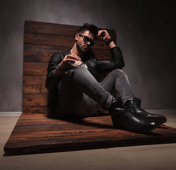 Vista lateral de un hombre de moda sentado en chaqueta de cuero —  Fotos de Stock
