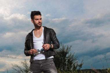 güneş gözlüğü tutan deri ceketli yakışıklı adamı 