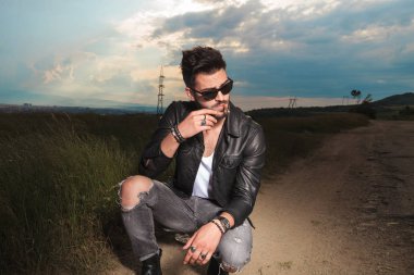 deri ceket ve güneş gözlüğü genç adam sigara içiyor 