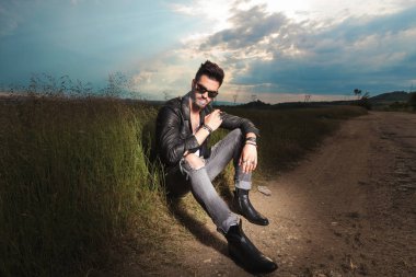 adam köy yolunda ve sigara kenarında oturur