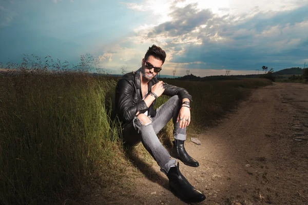 adam köy yolunda ve sigara kenarında oturur