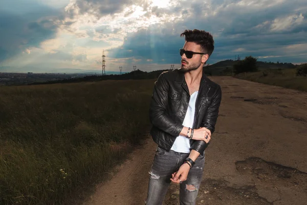 Man in leather jacket and  sunglasses holds his elbow — Stock Photo, Image