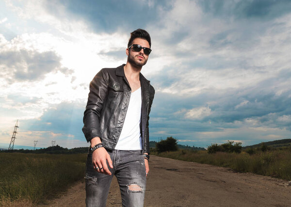 man in leather jacket walking on a country road 