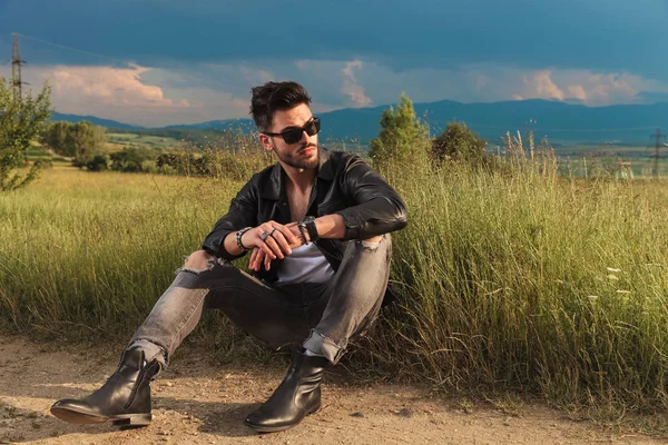 Sedící muž nosí koženou bundu vypadá daleko na stranu — Stock fotografie