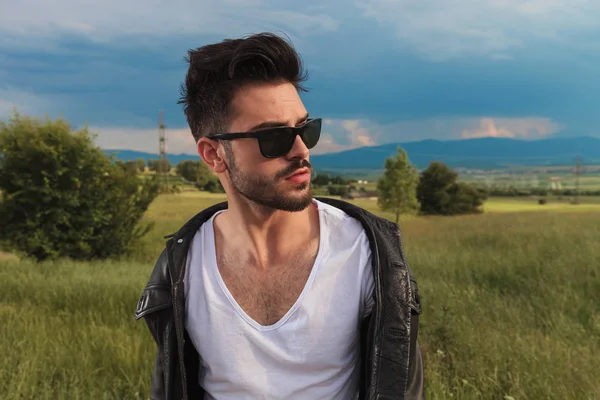 Man wearing sunglasses and leather jacket and looks away — Stock Photo, Image