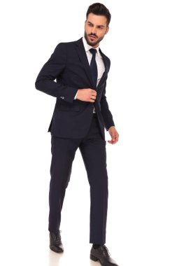 uzağa bakarak yürüyen bir genç iş adamı yan görünüm 