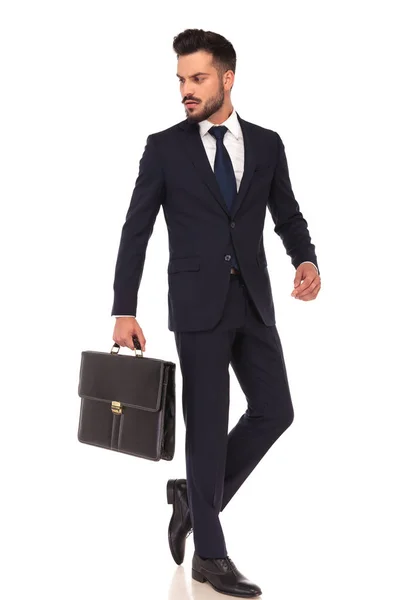 Joven hombre de negocios que lleva maletín está caminando y mira hacia atrás —  Fotos de Stock