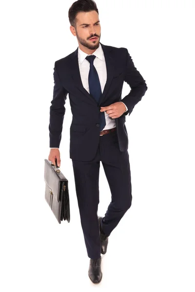 Hombre de negocios de moda con traje de desabotonamiento maleta mientras camina —  Fotos de Stock