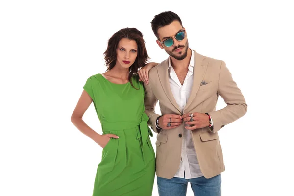 Man wearing sunglasses buttoning  coat while woman leans on him — Stock Photo, Image