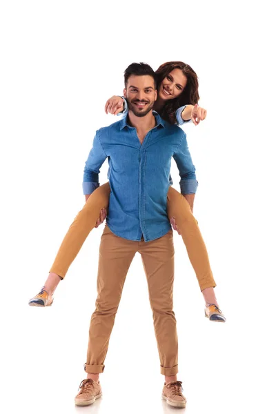 Casual man carrying his woman while she is pointing — Stock Photo, Image