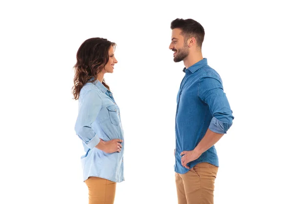 Casual couple standing with hands on waist facing each other — Stock Photo, Image