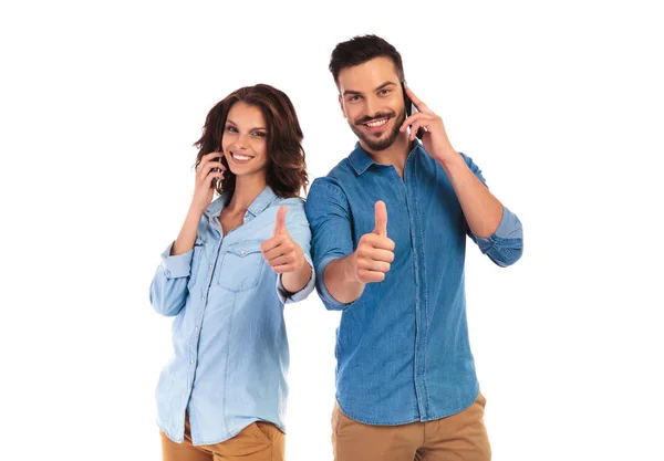Gelukkige paar praten op telefoons en maken de ok teken — Stockfoto
