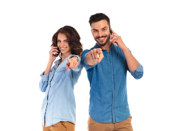 Casual man and woman talking on their phones are pointing — Stock Photo, Image