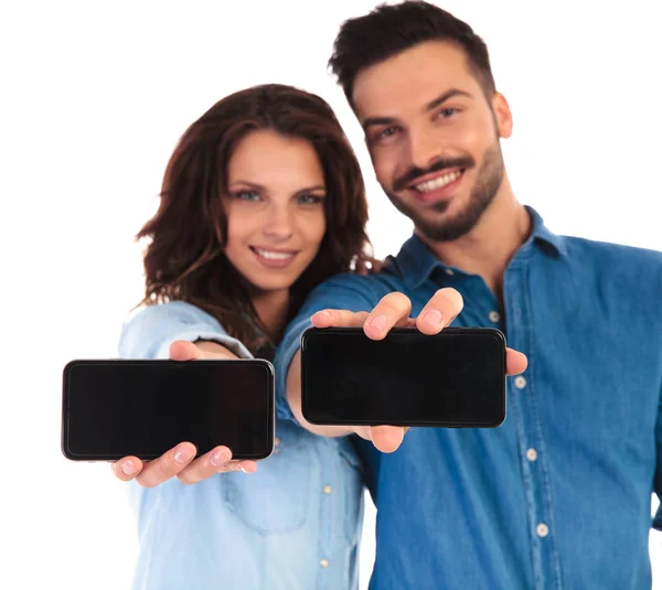 Casual man and woman showing their phones — Stock Photo, Image