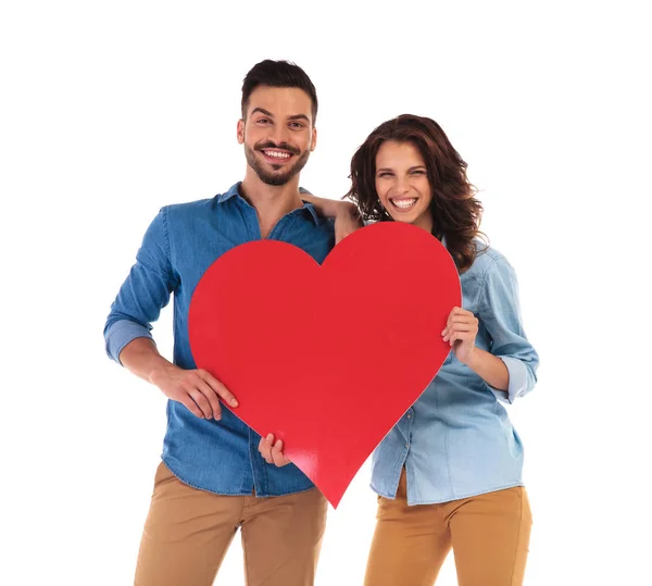 Rindo casal casual segurando um grande coração vermelho — Fotografia de Stock
