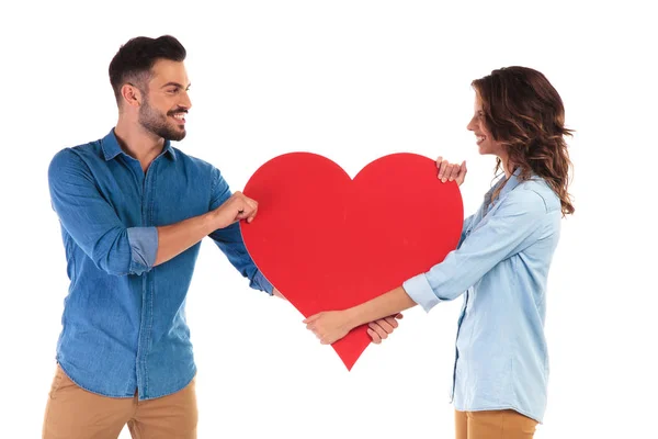 Lyckliga paret slåss om ett stort rött hjärta — Stockfoto