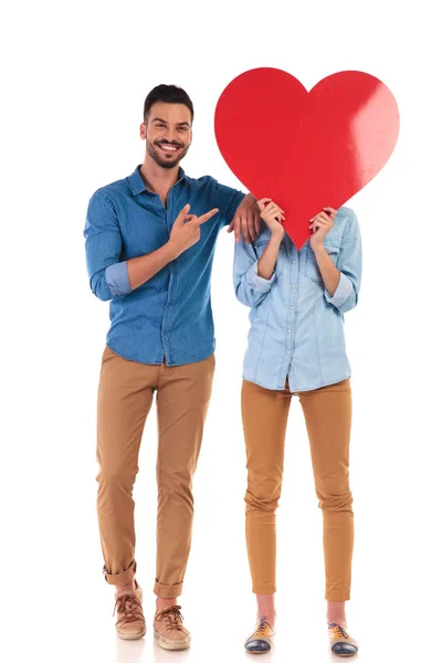 Lächelnder Mann zeigt auf das große Herz über dem Gesicht der Frau — Stockfoto