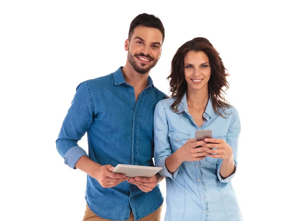 Sonriente hombre sosteniendo tableta y mujer mensajes de texto en el teléfono — Foto de Stock