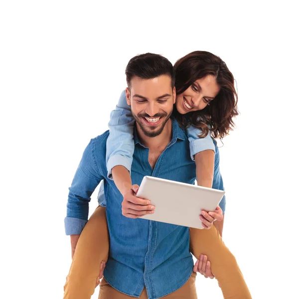 Jovem casal casual rindo enquanto lendo juntos em um tablet — Fotografia de Stock