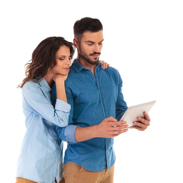 Casual woman leaning on man's shoulders to read on  tablet — Stock Photo, Image