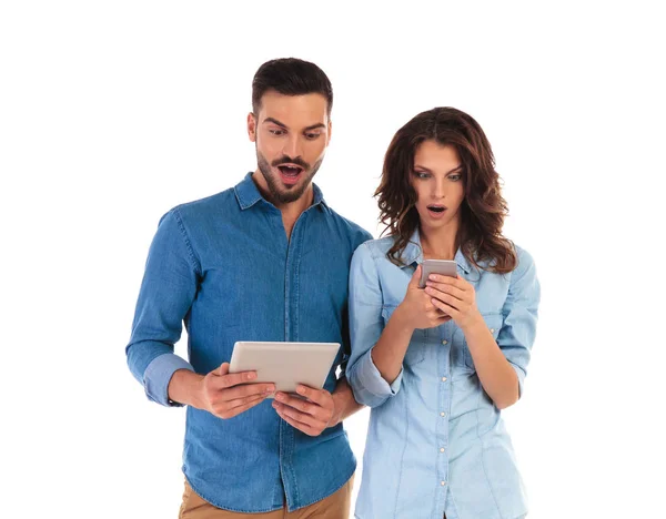 Amazed casual couple reading surprising things on their mobile d — Stock Photo, Image