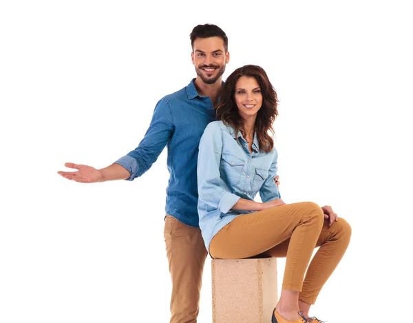 Standing casual man presenting something near his seated woman — Stock Photo, Image