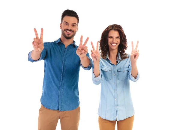 Happy laughing casual couple making the victory sign — Stock Photo, Image