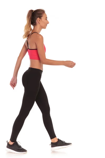 Vista lateral de una delgada mujer joven fitness caminando —  Fotos de Stock