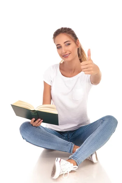 Ευτυχισμένος νεαρή γυναίκα κάνει εντάξει σημάδι διαβάζοντας ένα βιβλίο — Φωτογραφία Αρχείου