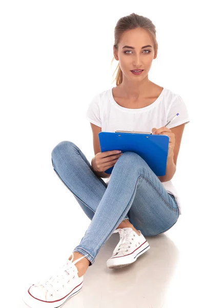 Сидящая молодая женщина делает заметки на планшете — стоковое фото