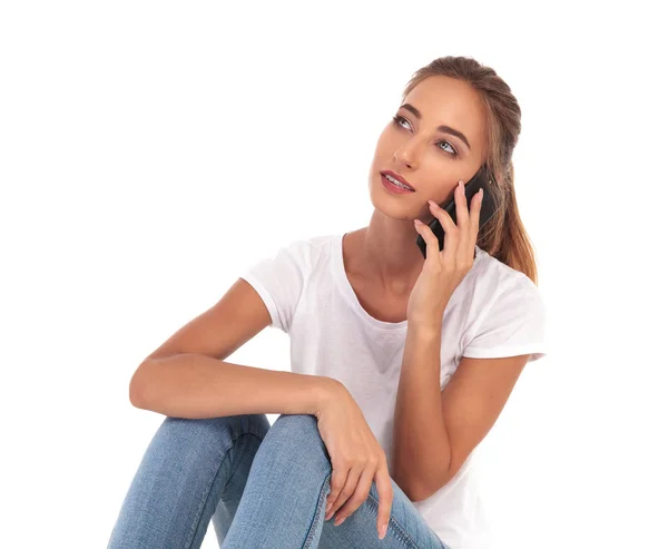 Mujer sentada hablando por teléfono mira hacia un lado —  Fotos de Stock