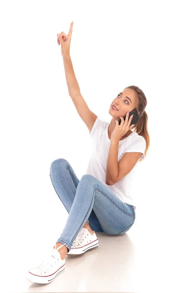 Mujer sonriente hablando por teléfono está apuntando hacia arriba —  Fotos de Stock