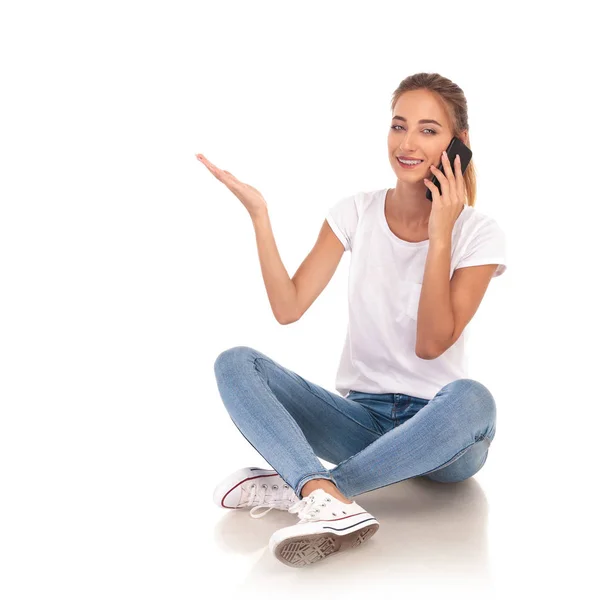 Sentada mujer casual hablando por teléfono está presentando algo —  Fotos de Stock