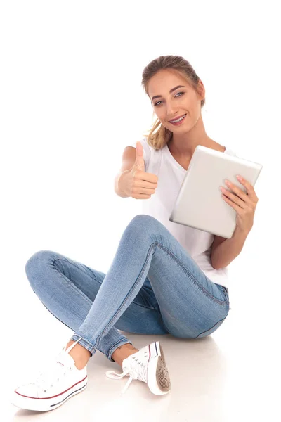 Mujer feliz sentada con la tableta y hace signo ok — Foto de Stock