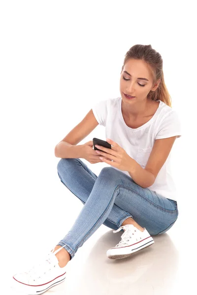 Joven mujer rubia casual leyendo mensajes en su teléfono — Foto de Stock