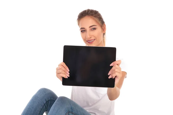 Mujer casual feliz mostrando la pantalla en blanco de una tableta — Foto de Stock